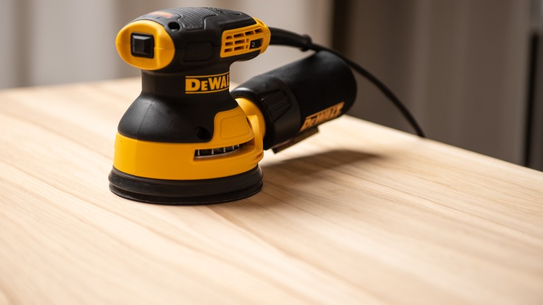 DeWalt orbital sander sitting on wood surface