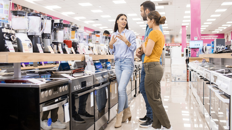 Couple speaking to salesperson about stoves