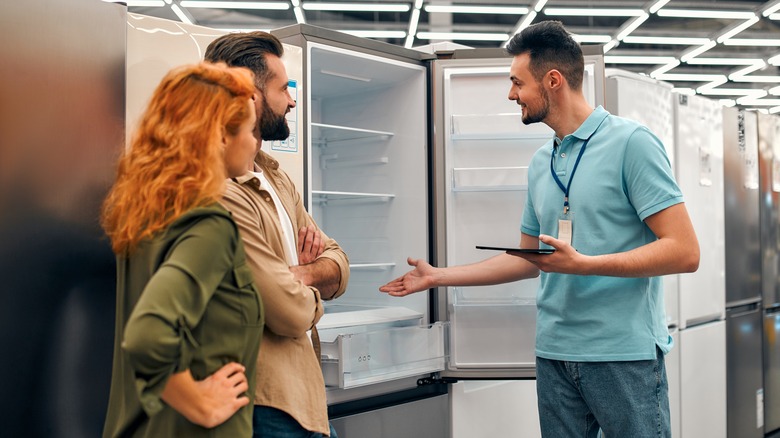 salesperson demonstrating fridge to couple