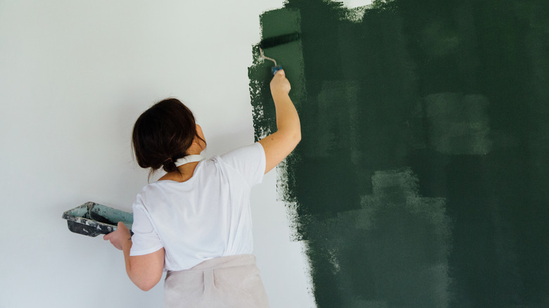 Woman painting green accent wall