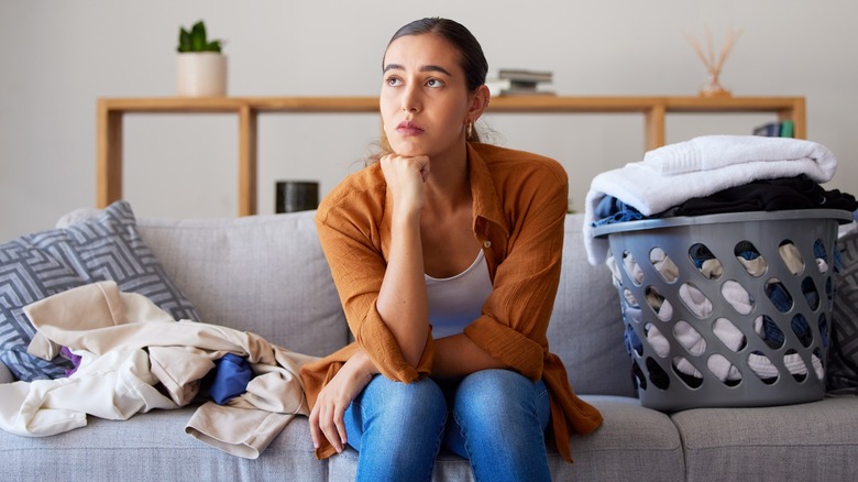 Thinking woman surrounded by laundry