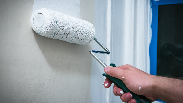 person rolling paint on wall