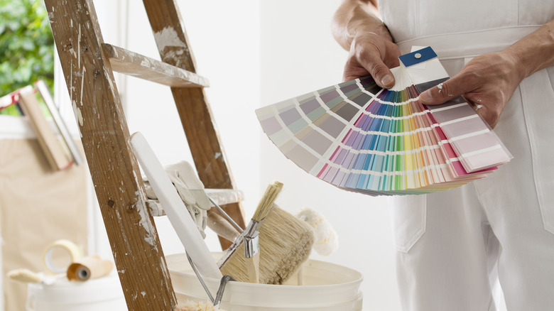 Hands of house painter holding swatches