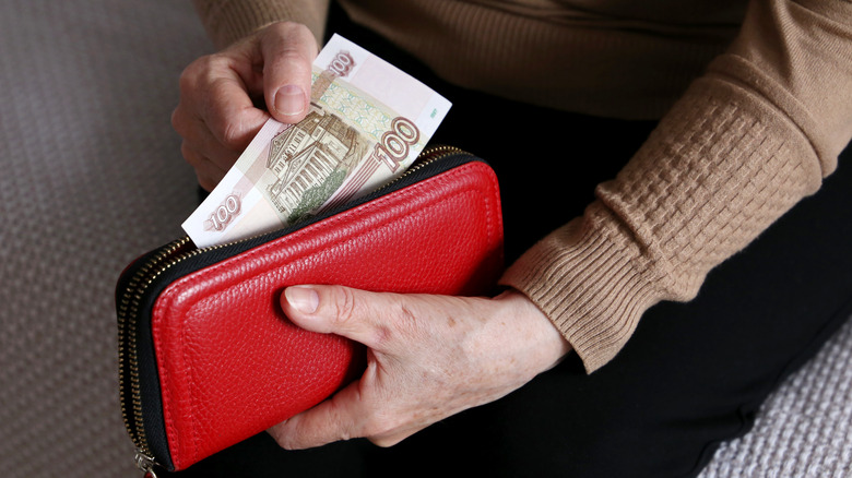 woman handling money in wallet