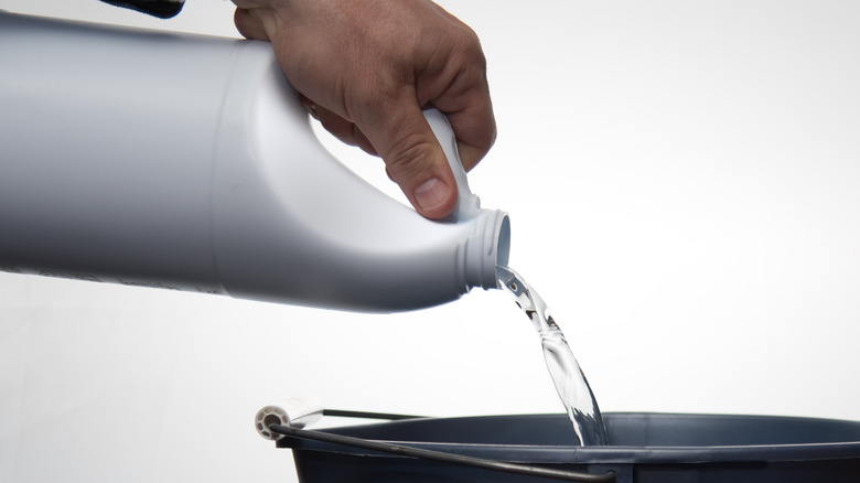 Hand pouring bleach in bucket