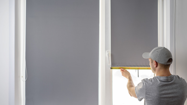 person putting up blackout blinds