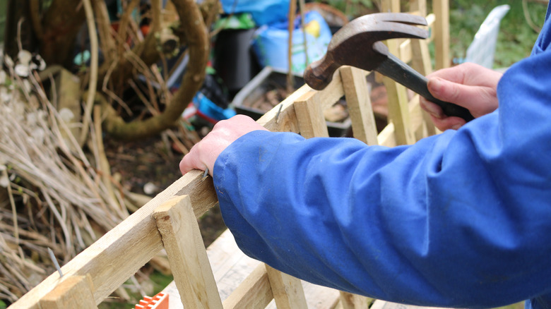 person hammering nail into trellis