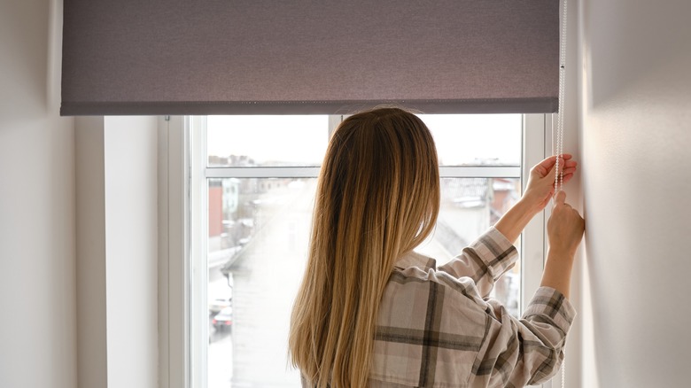 woman lowering window shade