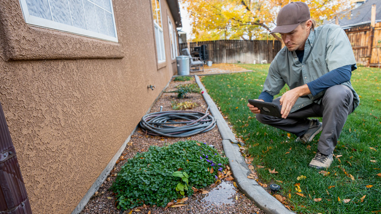 man inspecting leak near foundation