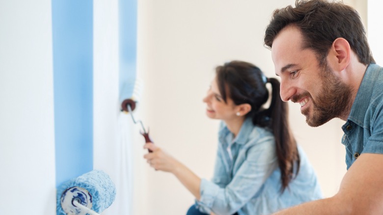 Couple painting walls blue together 