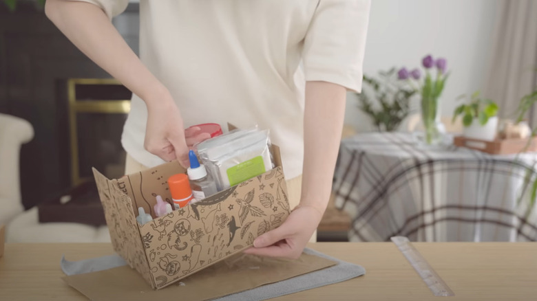 Person showing off an upcycled shoe box turned into a storage box for art supplies.