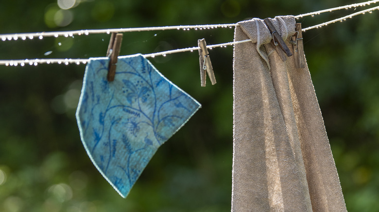 A blue Swedish dishcloth hanging on a clothesline with a towel