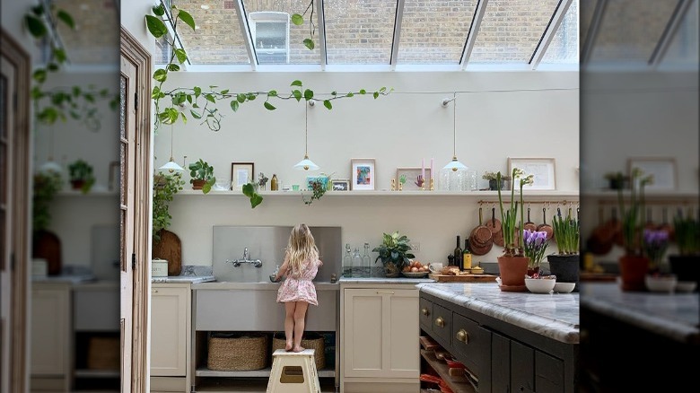 Child washing hands in sunroom kitchen