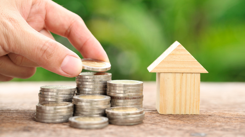 hand stacking coins by house