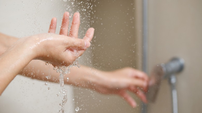 Woman's hand underneath shower spray