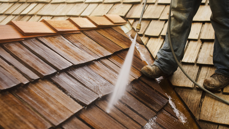 Man cleans wood roof shingles