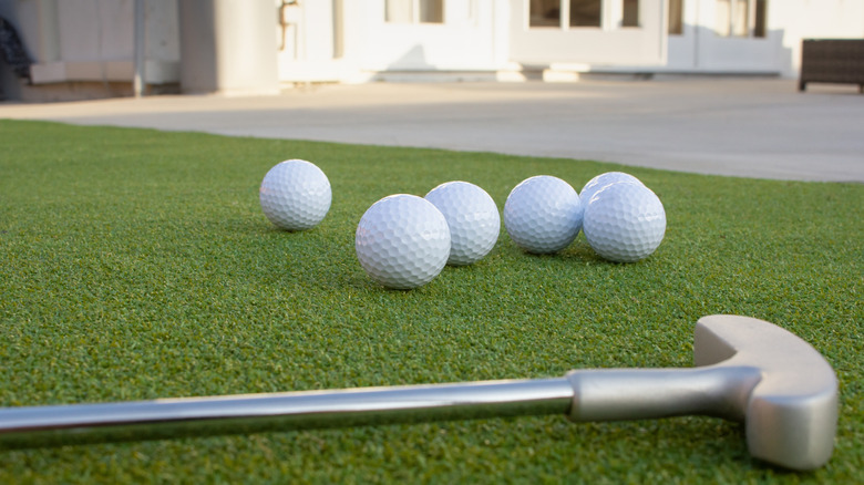 Close-up of golf club and golf balls in backyard