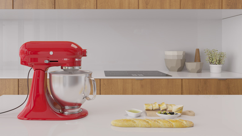 A red KitchenAid stand mixer on a countertop with fresh bread