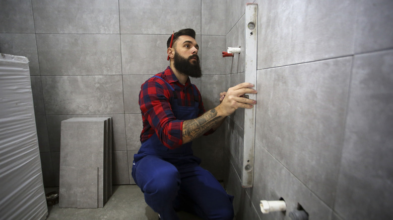 man measuring bathroom wall