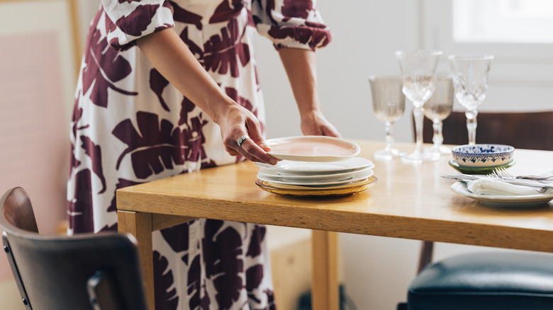 lady setting up a wooden table with dinnerware