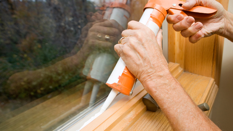 person caulking window wood frame