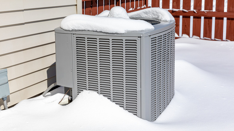 An external AC unit in a snow-filled yard