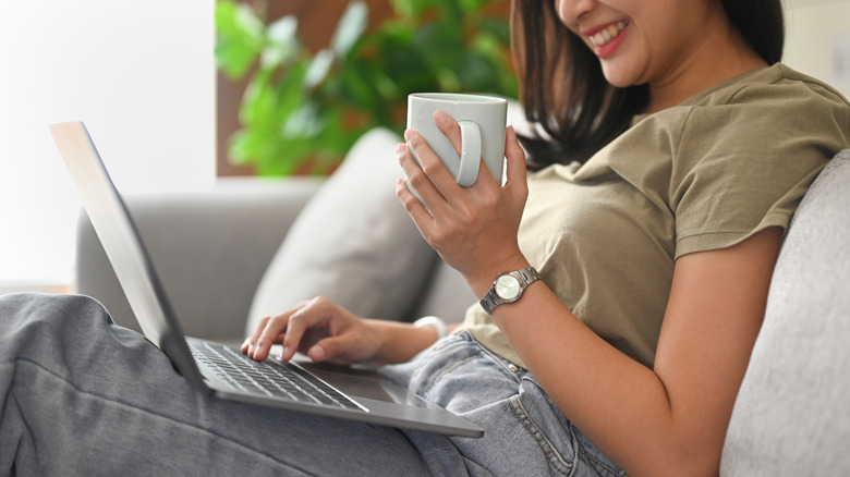 Woman on laptop sipping coffee