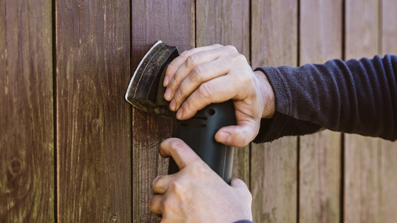 man sanding wood shed