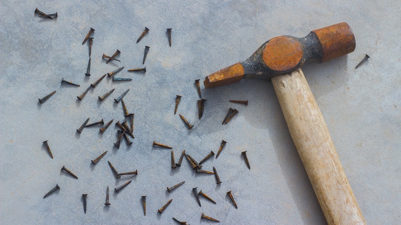 rusty hammer on nail pile