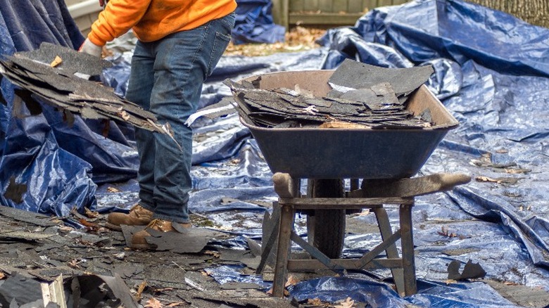 worker removing roof shingle debris