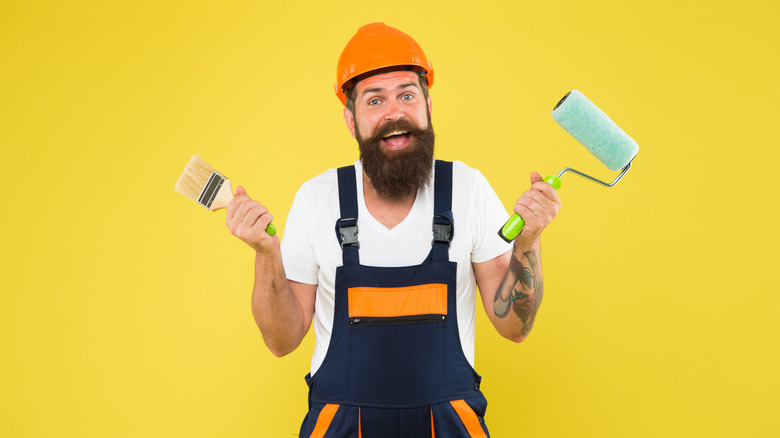 man holding paintbrush and roller