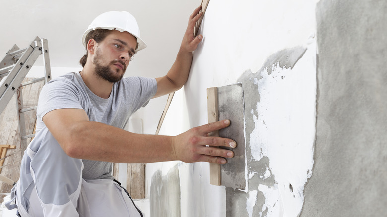 person scraping a wall