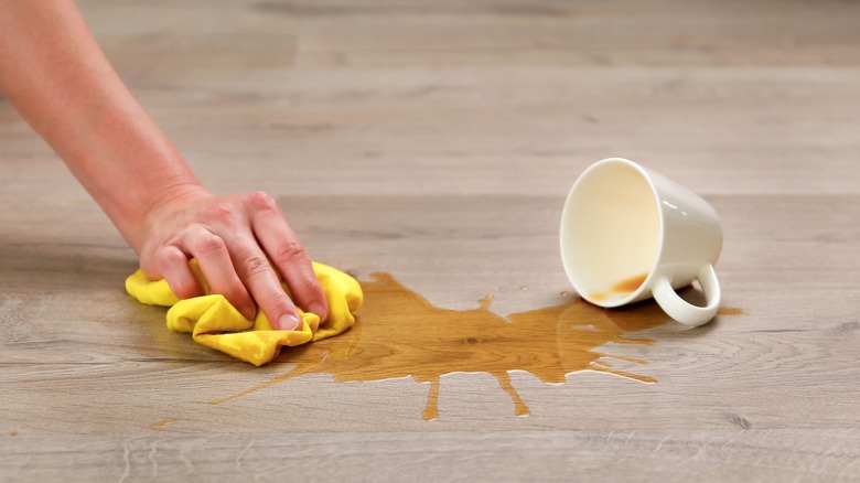 person cleaning up spilled coffee on floor