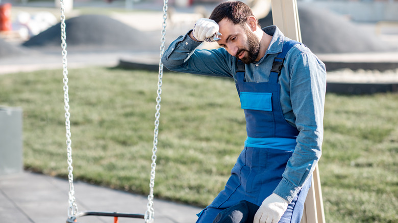 Tired contractor near swing set