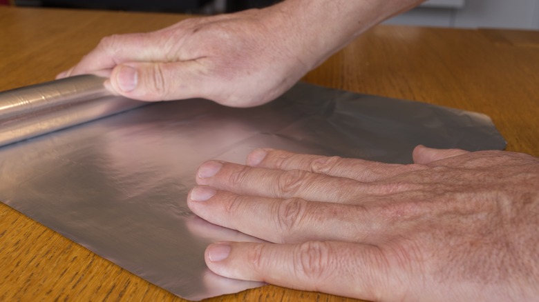 Person unrolling foil