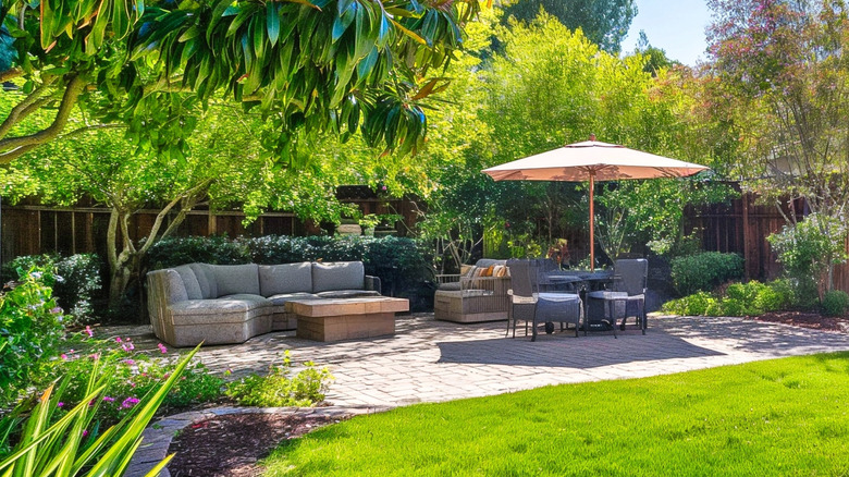 A shady backyard patio oasis with lush greenery and furniture