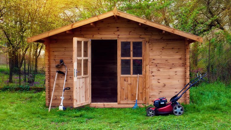 Wooden shed with lawn mower