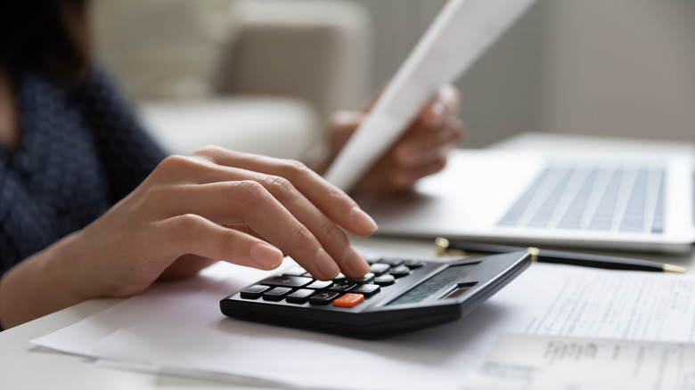 Person completing paperwork with calculator