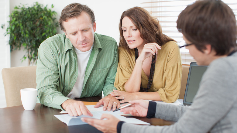 couple discussing paperwork with another adult