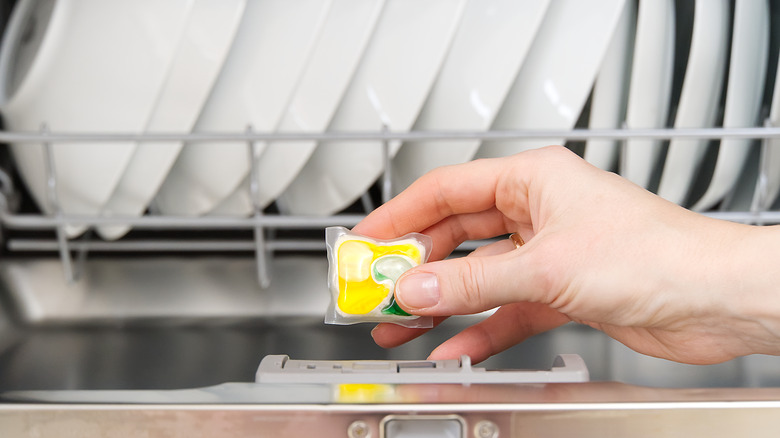 A woman placing a dish pod into the dishwasher