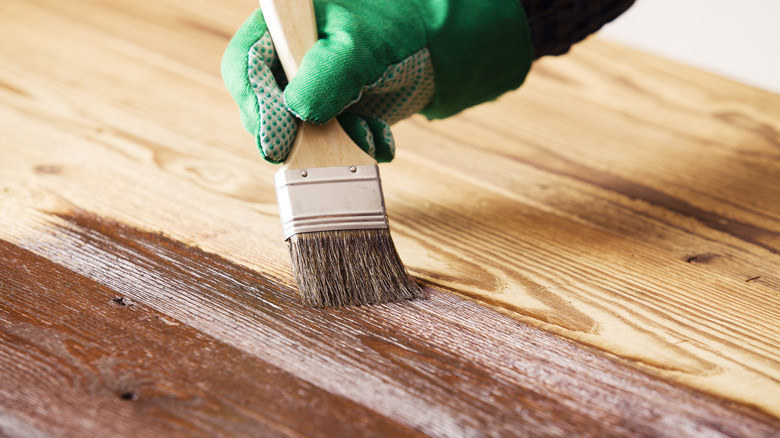 person staining wood with brush