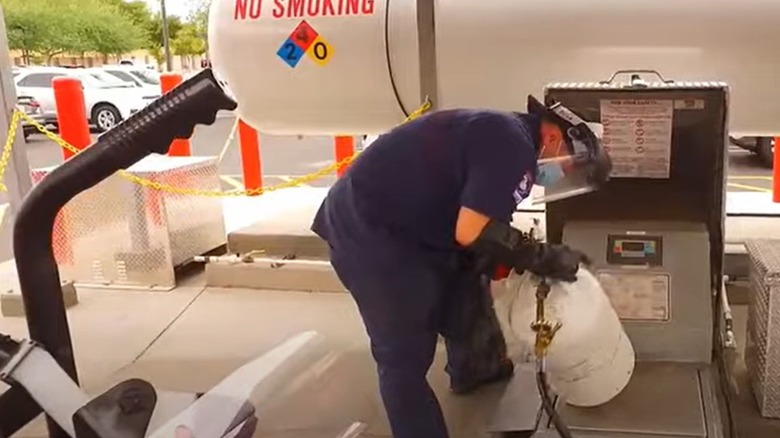 Man filling a small propane tank from a large tank at Costco