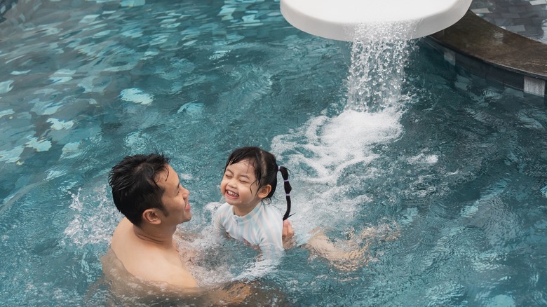 Dad catching daughter from water slide