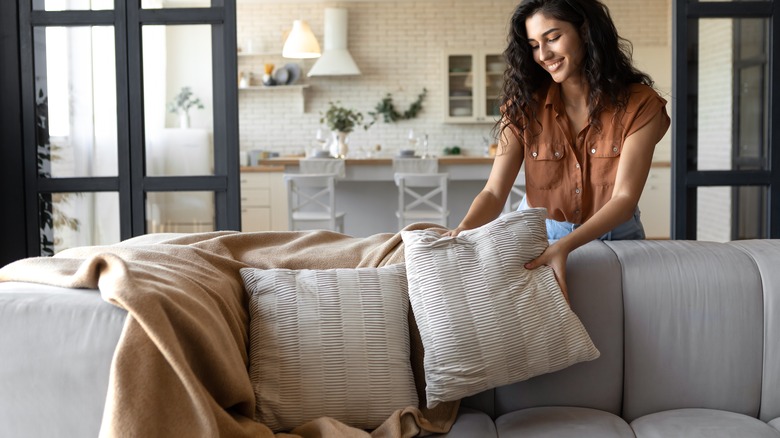 woman arranging pillows on couch