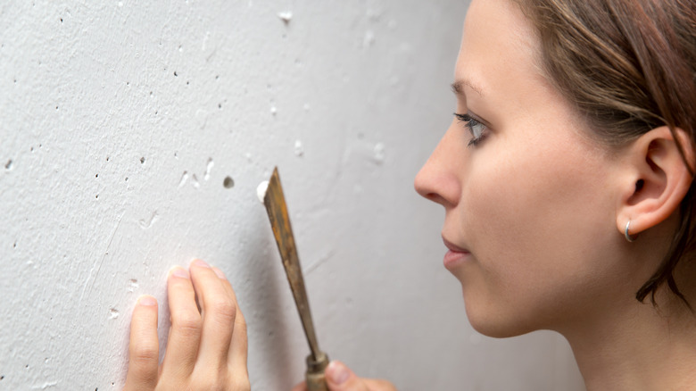 woman repairing hole in wall