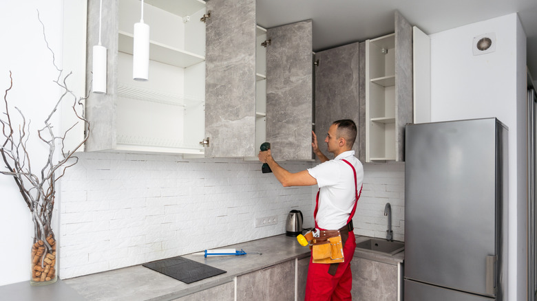 A contractor installing frameless marble kitchen cabinets