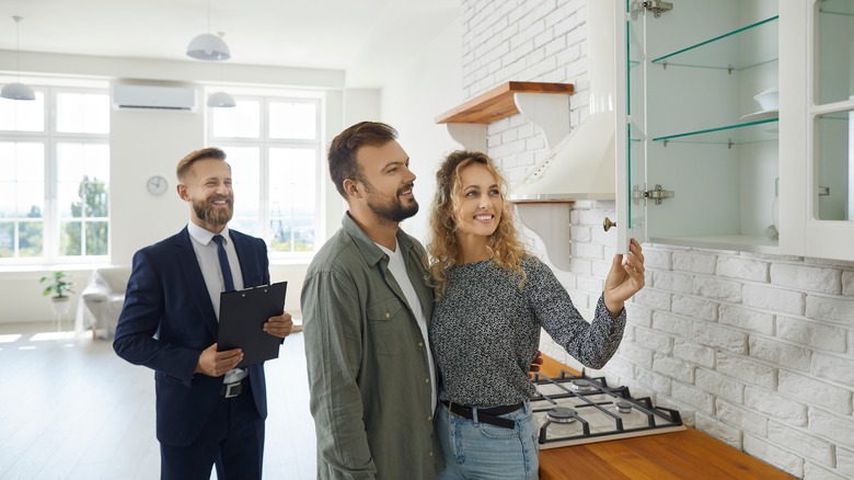 Couple opening cabinet in kitchen