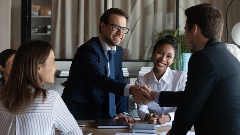 two men shaking hands across table