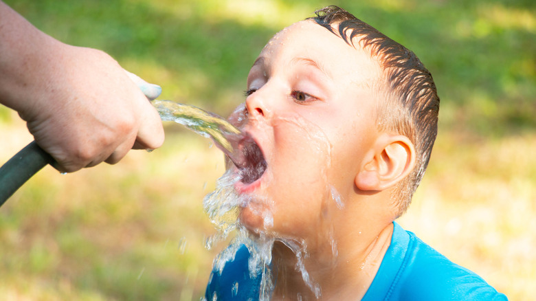 Boy drinking from a hose