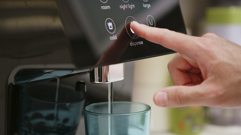 person using refrigerator water dispenser